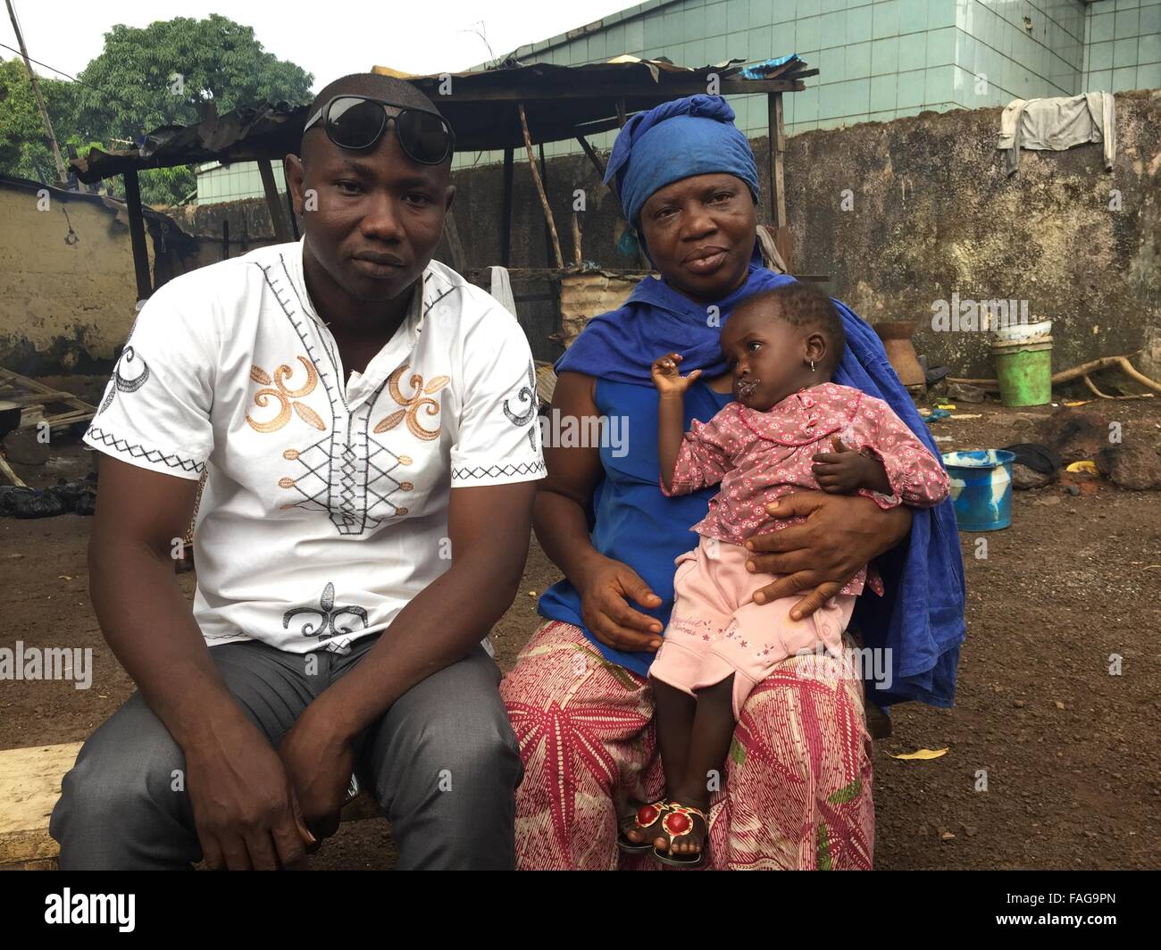 Conakry, Guinea. 12th Nov, 2015. Mohamed Bangoura (L) sits next to his daughter Fatuma and his sister-in-law M'mah Cisse at his farm in Conakry, Guinea, 12 November 2015. The 34-year-old man provides for ten orphans after the Ebola epidemic killed numerous family members. Photo: KRISTIN PALITZA/dpa/Alamy Live News Stock Photo