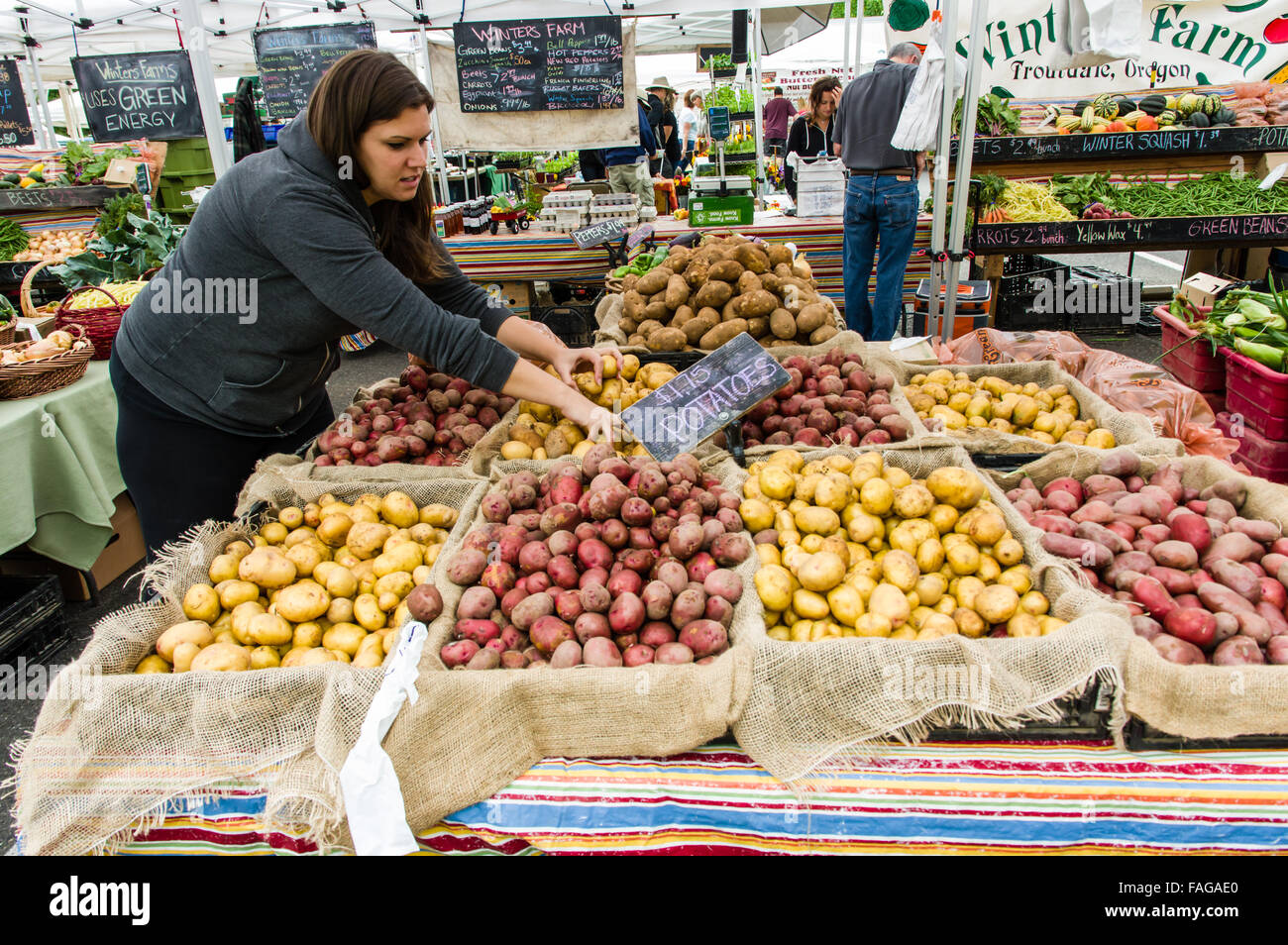 Woman stocking a potato display in a farmers market in Beaverton, Oregon, USA Stock Photo