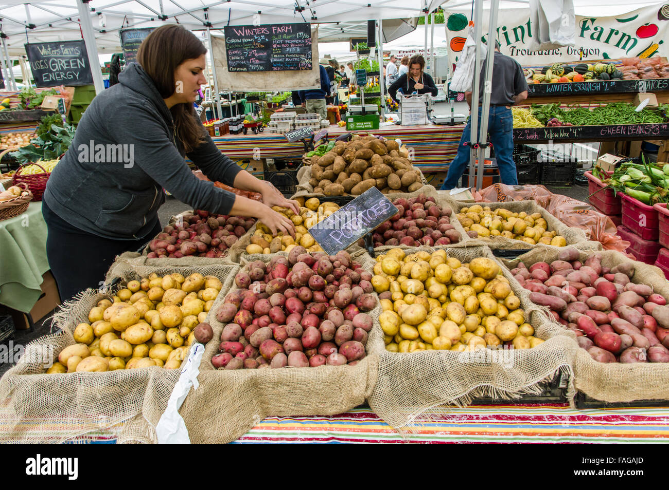 Woman stocking a potato display in a farmers market in Beaverton, Oregon, USA Stock Photo