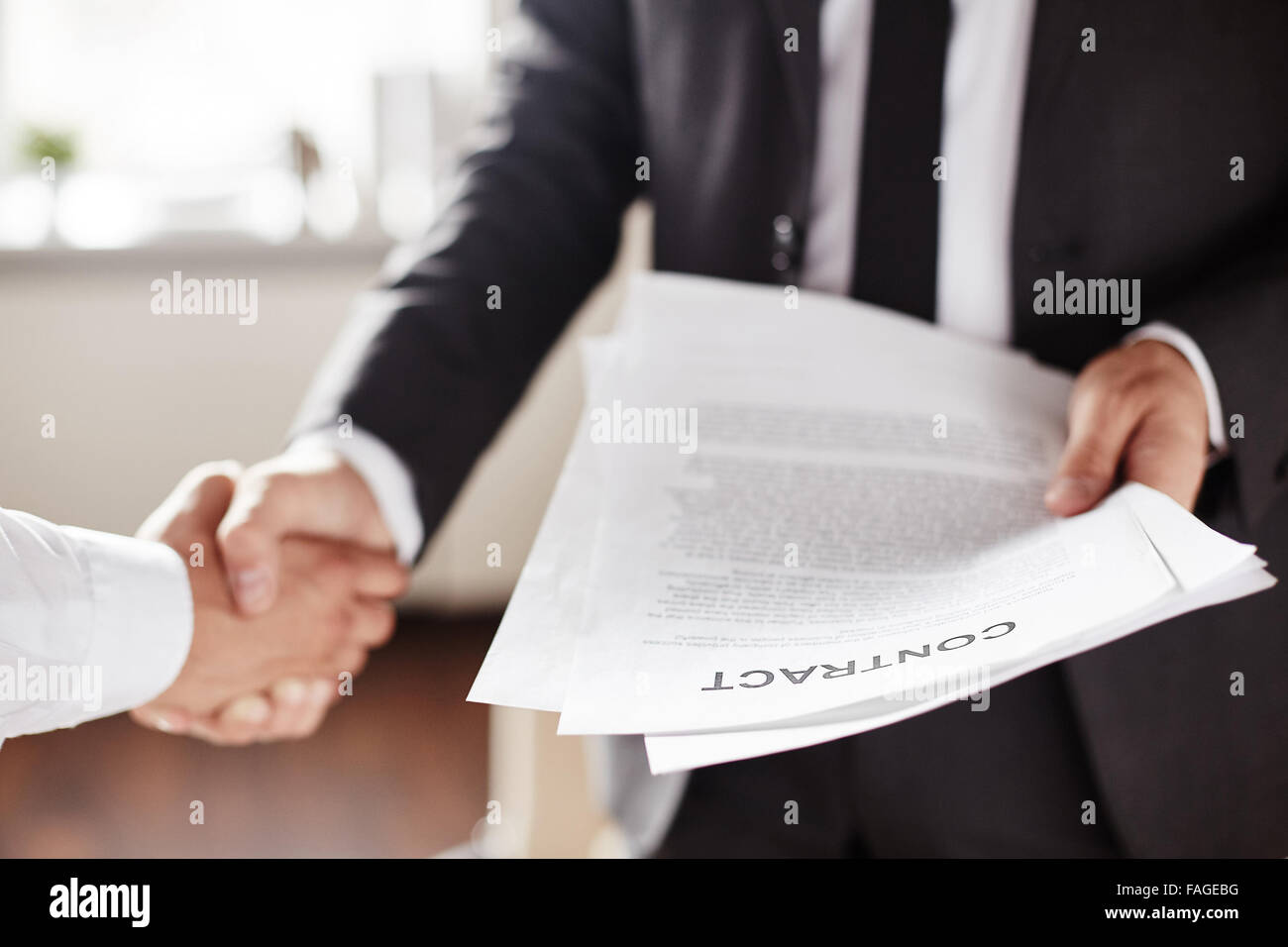 Business contract held by businessman during handshake with partner Stock Photo