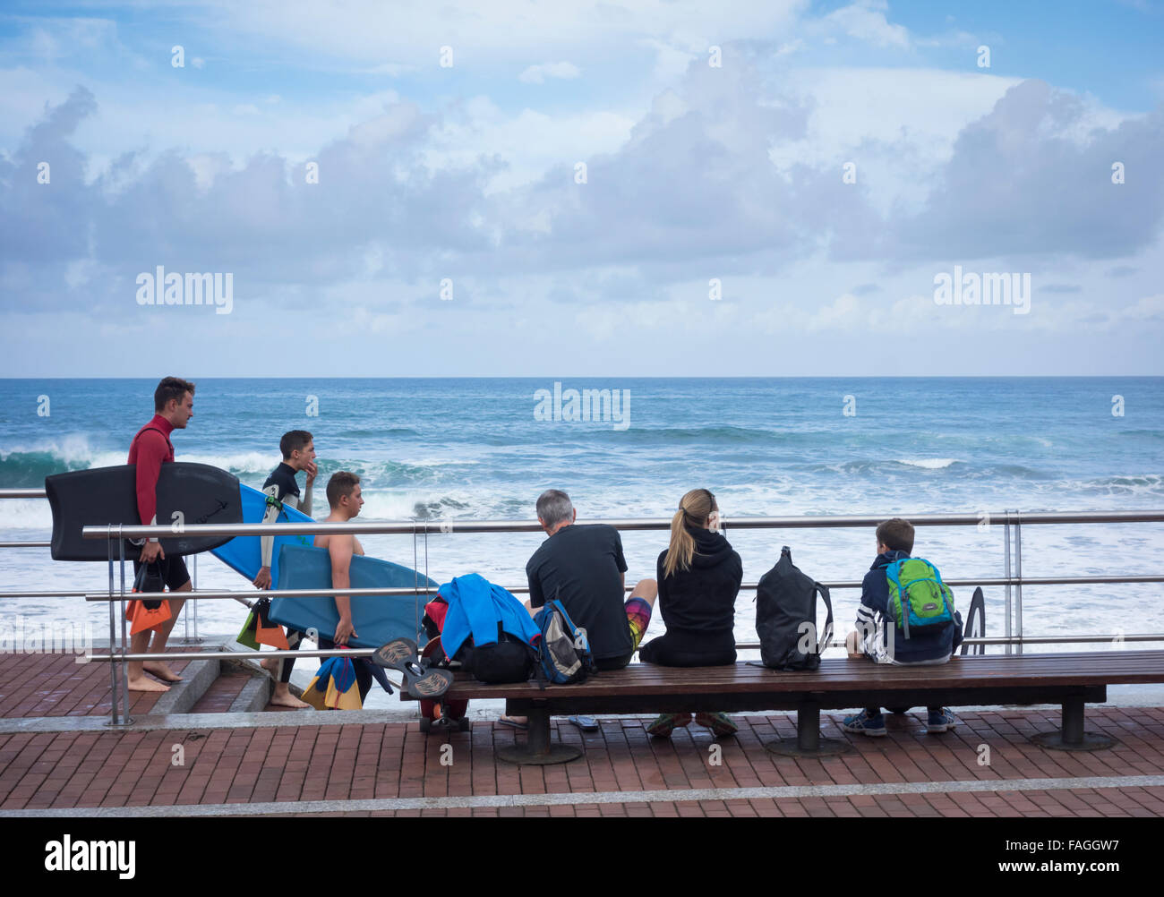 Young family watching surfers. La Cicer, Las Canteras, Las Palmas, Gran Canaria, Canary Islands, Spain Stock Photo