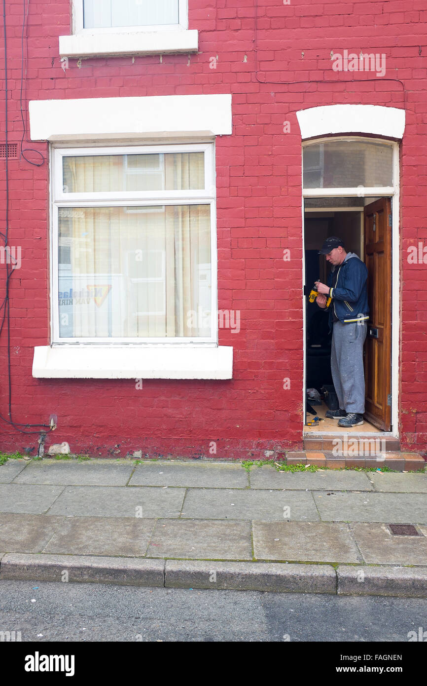 A worker or Landlord repairs the door frame of a terraced rental house on Wendell street in Liverpool 8, making improvements. Stock Photo