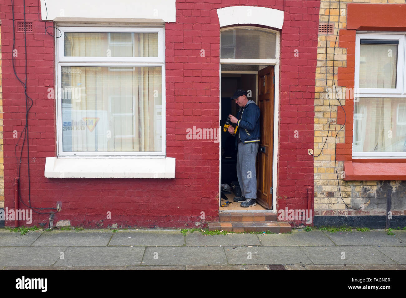 A worker or Landlord repairs the door frame of a terraced rental house on Wendell street in Liverpool 8, making improvements. Stock Photo