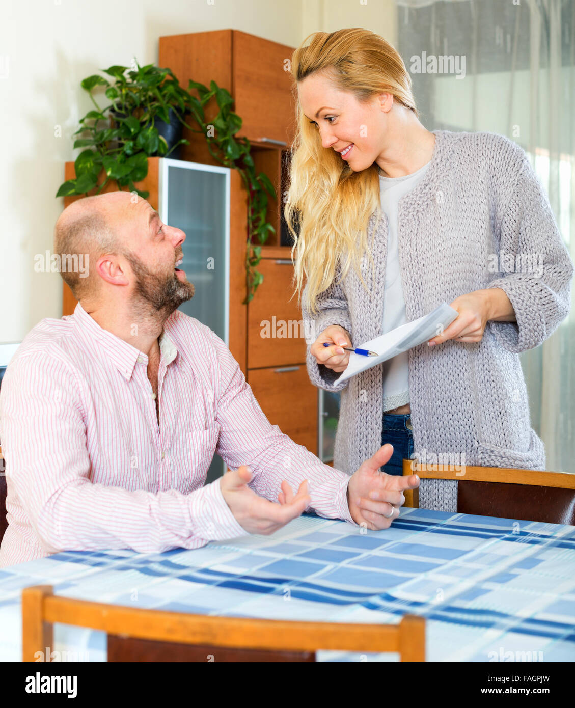 Husband and longhaired wife reading insurance contract at home Stock