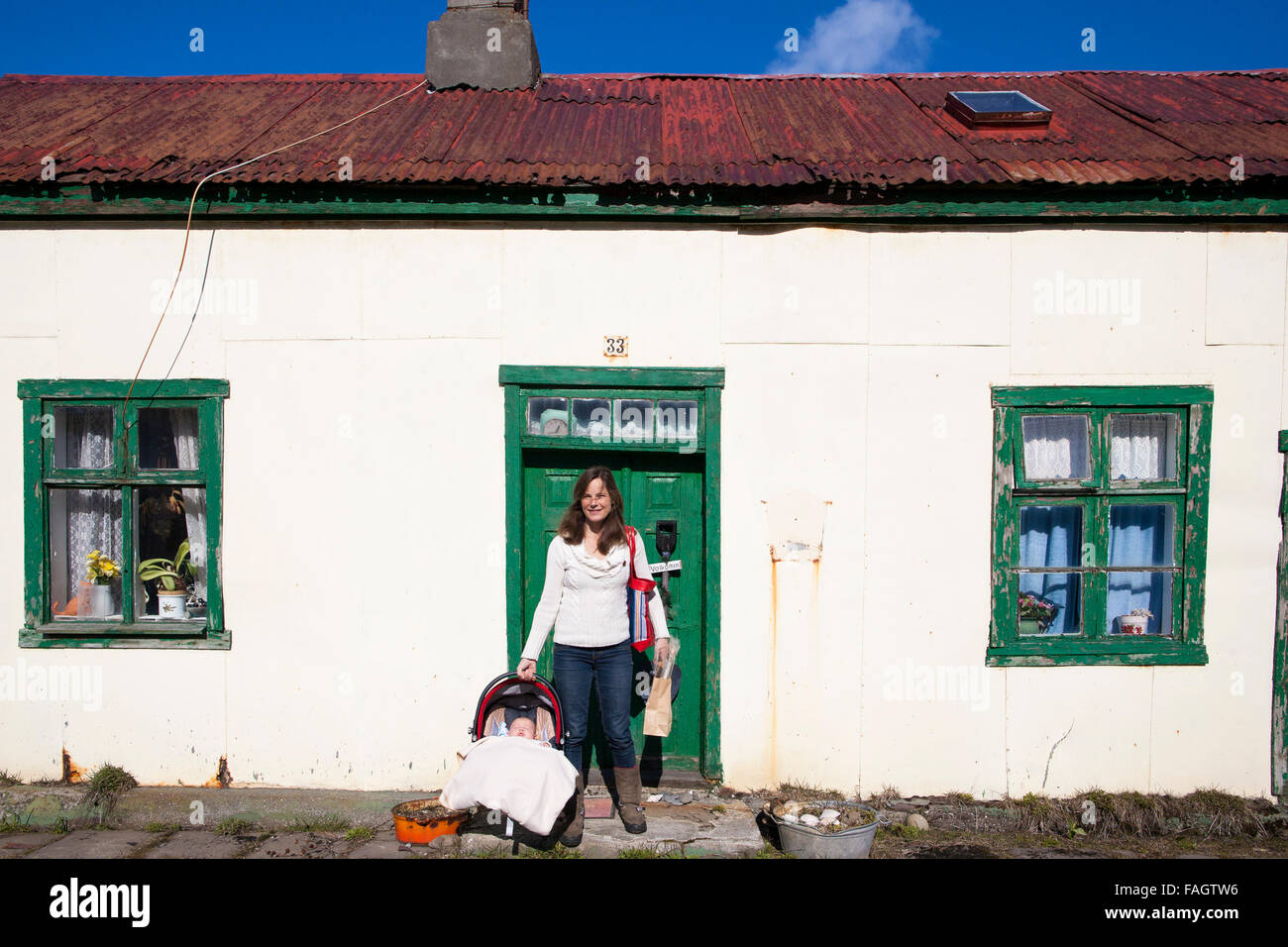 Mother with her young child stands outside one of the oldest houses in Isafjordur, famous for how many children were born  in it Stock Photo