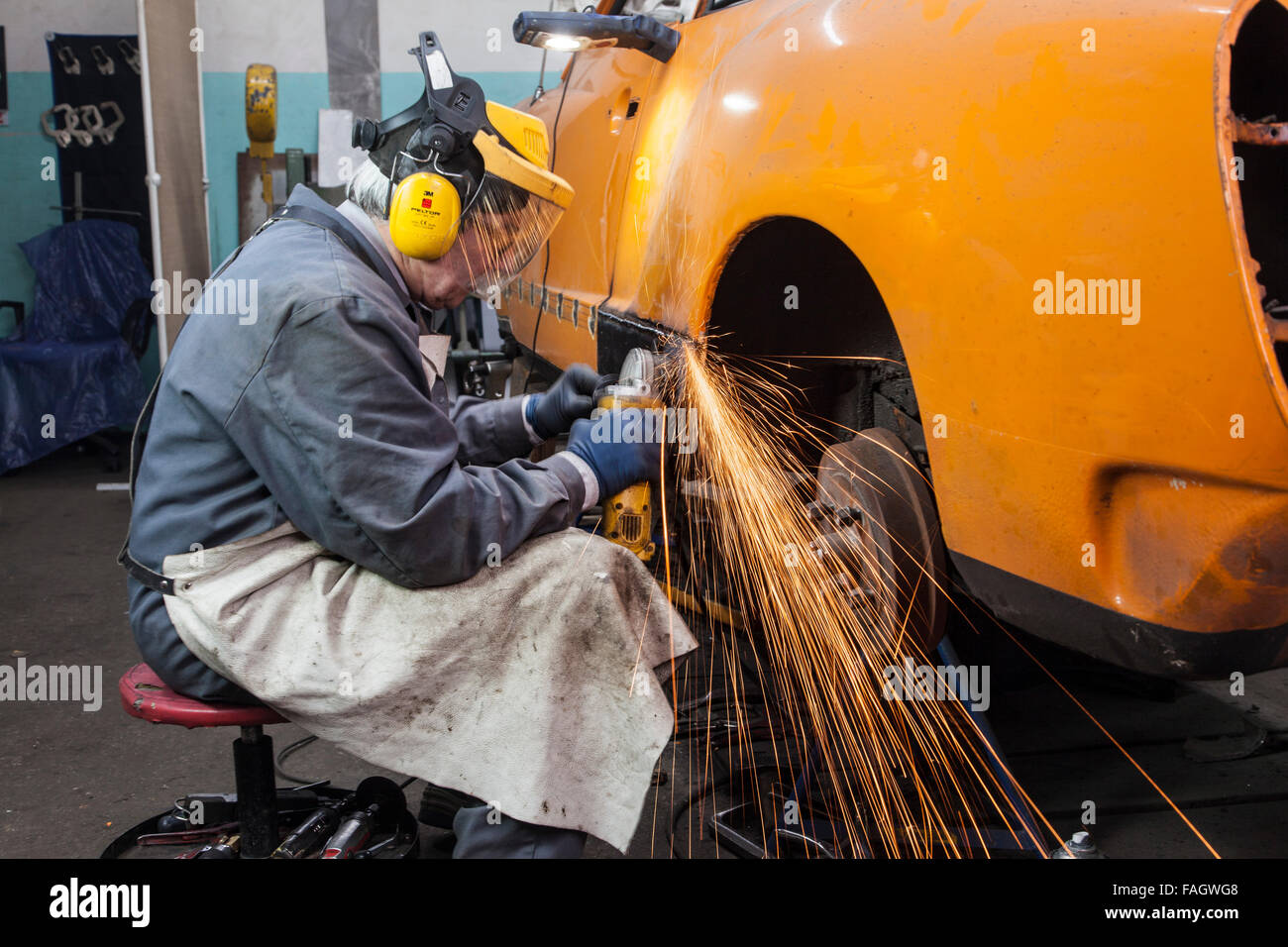 Coachbuilder restores a classic car VW Karmann Ghia. Welded seams are processed with angle grinder. Stock Photo