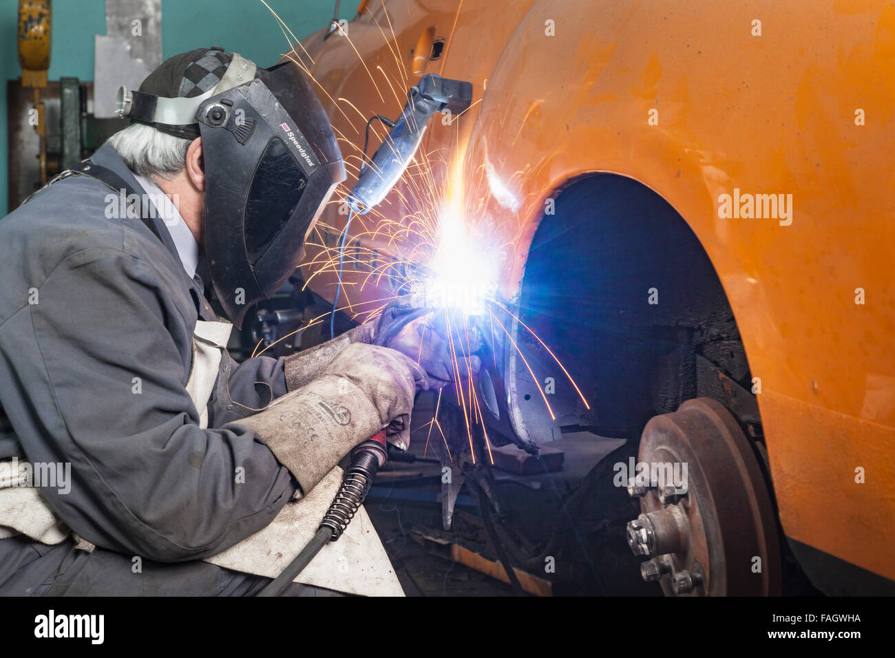 Coachbuilder restores an classic car VW Karmann Ghia. Welding work at the bodywork of the vehicle. Stock Photo