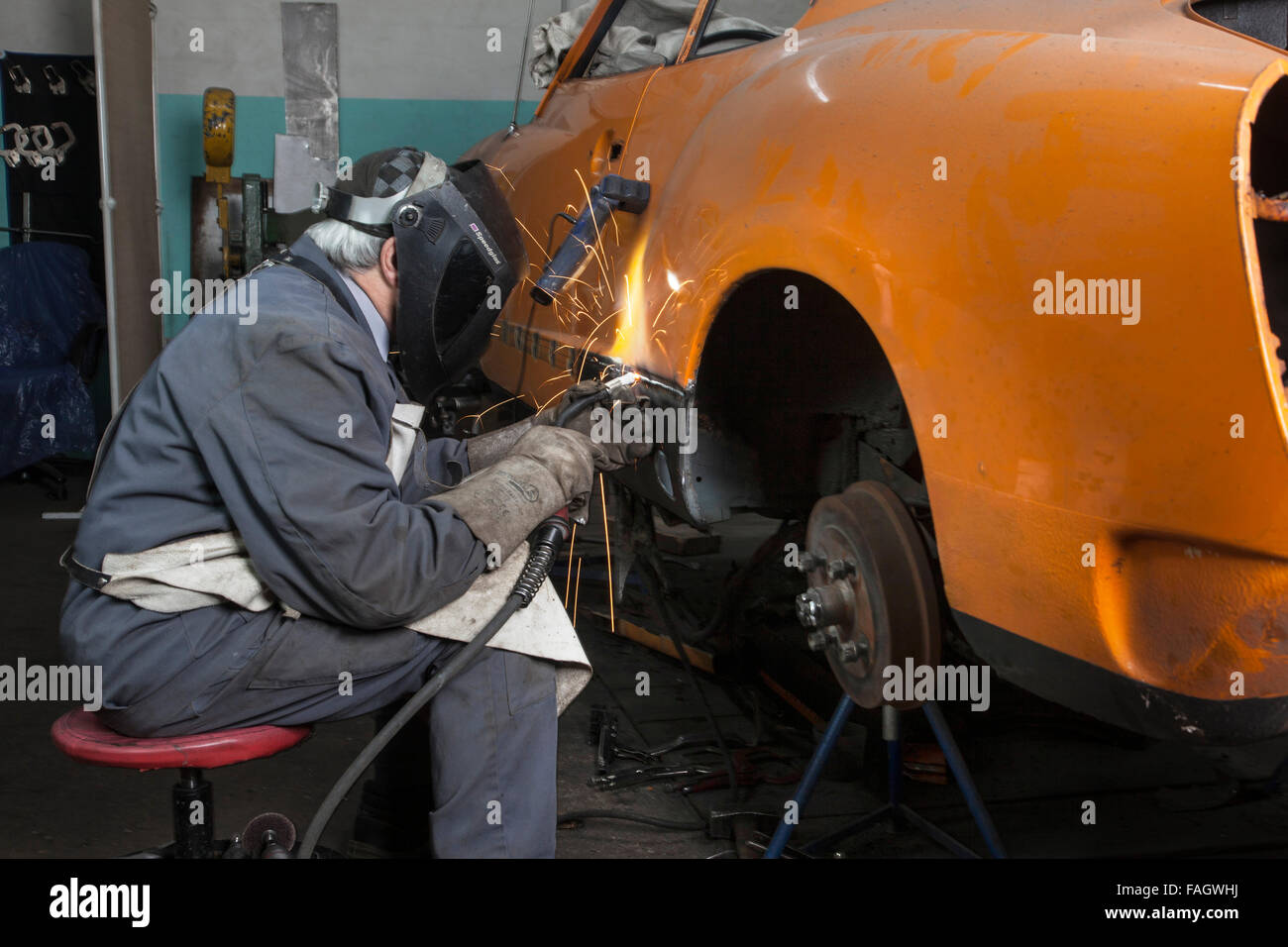Coachbuilder restores an classic car VW Karmann Ghia. Welding work at the bodywork of the vehicle. Stock Photo