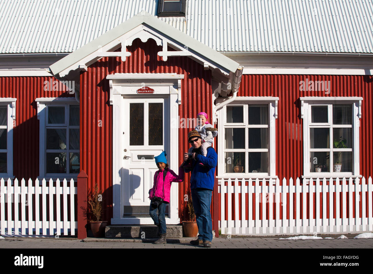 A father and daughters stand in front of a typical wooden and tin house in Isafjordur, the main town of the westfjords region Stock Photo