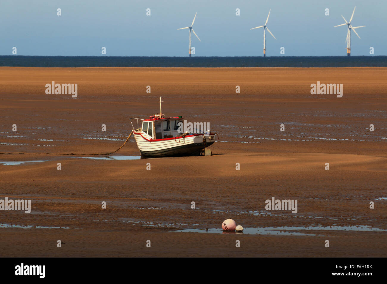 Stranded Fishing Boat and Offshore Wind Turbines Stock Photo