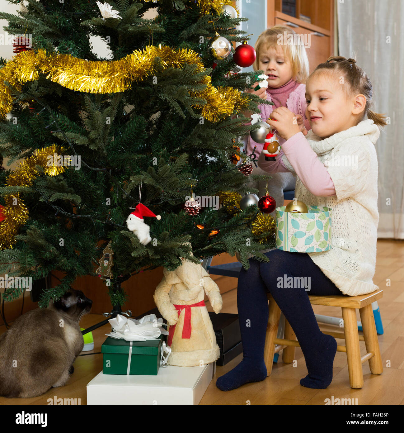 Two smiling little girls decorating Christmas tree at home Stock Photo ...