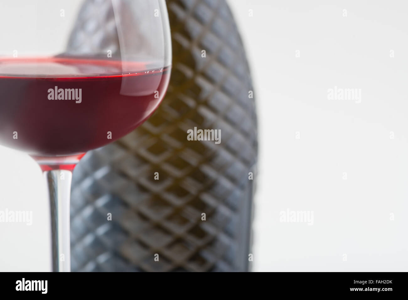 Glass with red wine and bottle behind it. Stock Photo