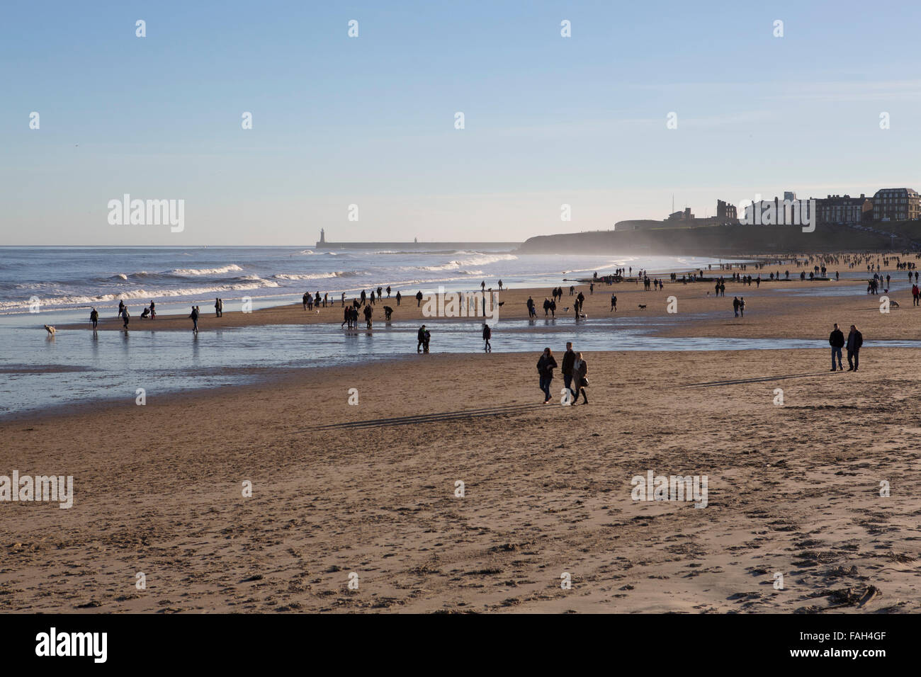 People walking on Tynemouth Beach in north-east England. Tynemouth Pier just into the North Sea. Stock Photo