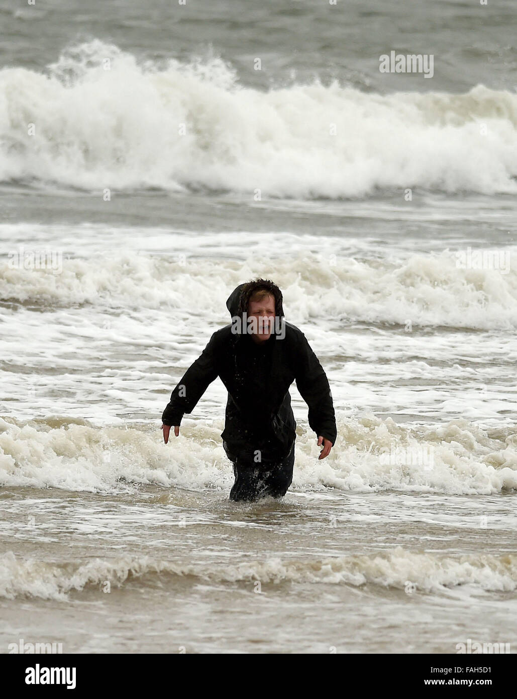 Boy in the sea fully clothed during stormy weather Stock Photo