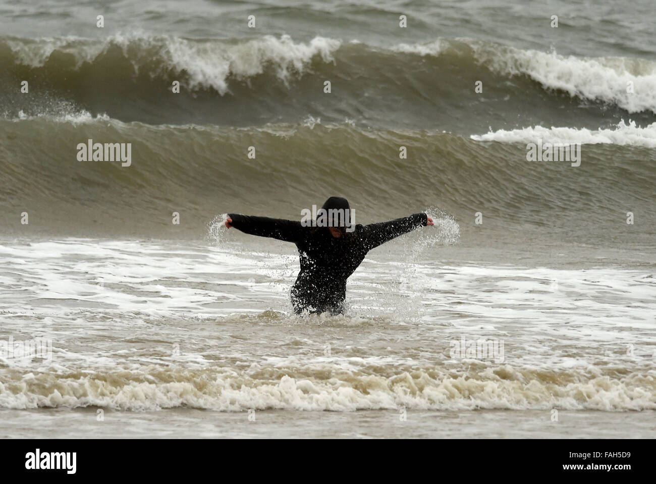 Boy in the sea fully clothed during stormy weather Stock Photo
