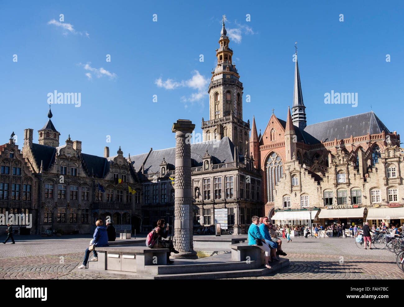 Tourist sitting by fountain in market square with Old Courthouse (Landhuis) and belfry. Grote Markt Veurne West Flanders Belgium Stock Photo
