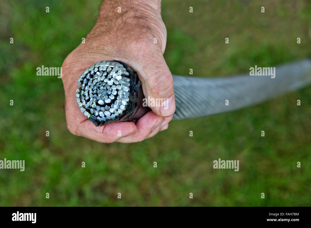 Man's hand grasping 1.752 inch 'Lang's  lay wire rope'  with steel core. Stock Photo