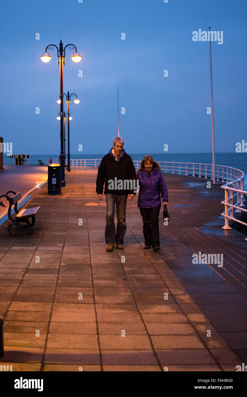Aberystwyth, Wales, UK. 30th Dec, 2015. UK Weather:  A couple walk hand in hand on the Prom at sundown making good use of the time whilst there is a break in the downpour we've had most of the day due storm Frank passing through. Credit:  Trebuchet Photography/Alamy Live News Stock Photo
