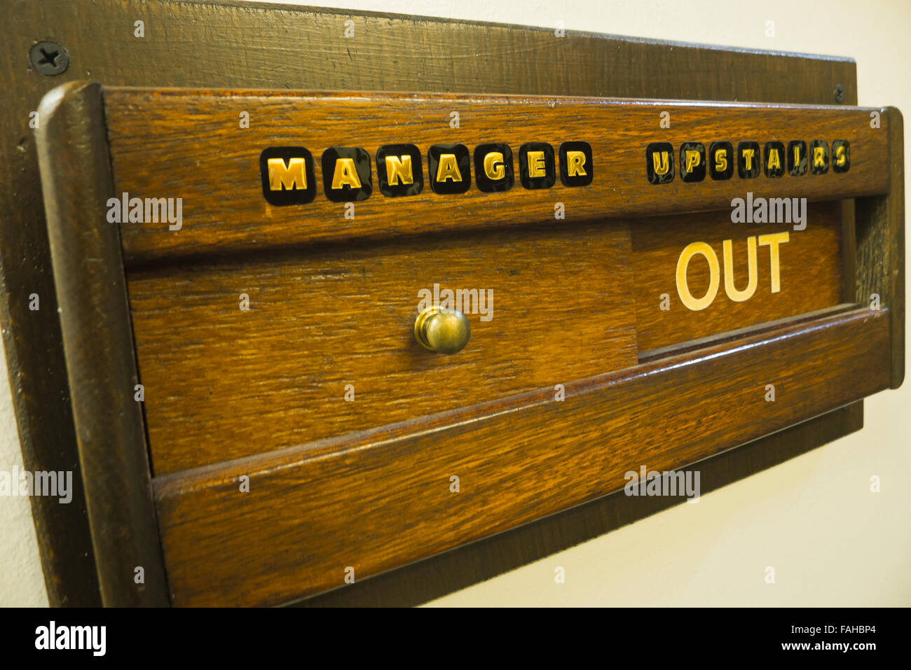 Wooden sliding sign 'MANAGER UPSTAIRS OUT'. Stock Photo