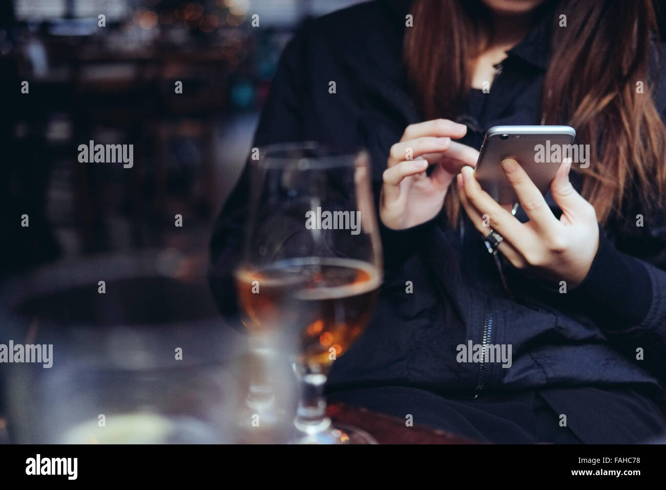 Young woman using a smartphone in bar Stock Photo