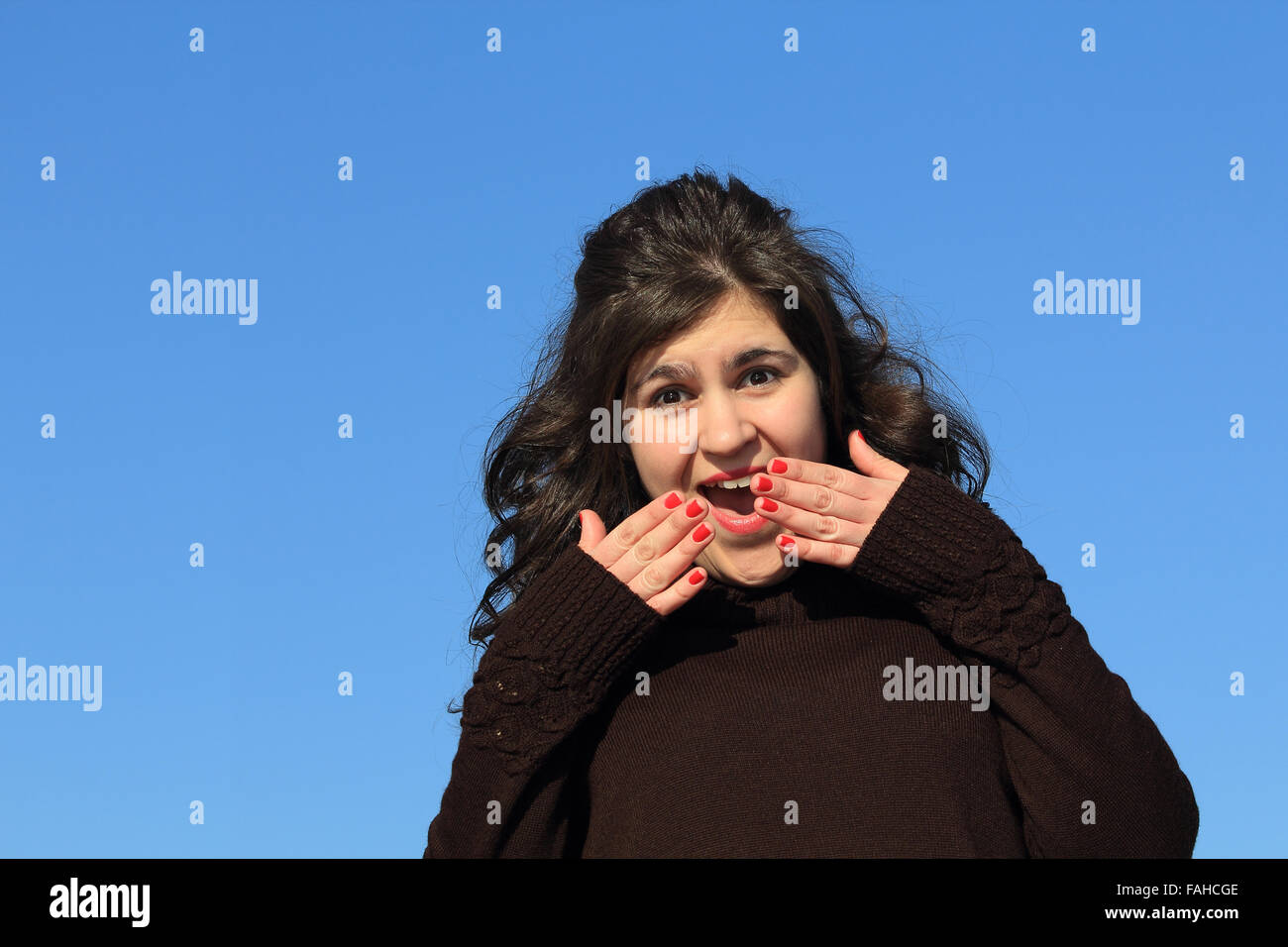 Girl with her hands over her mouth and eyes wide from shock. Stock Photo