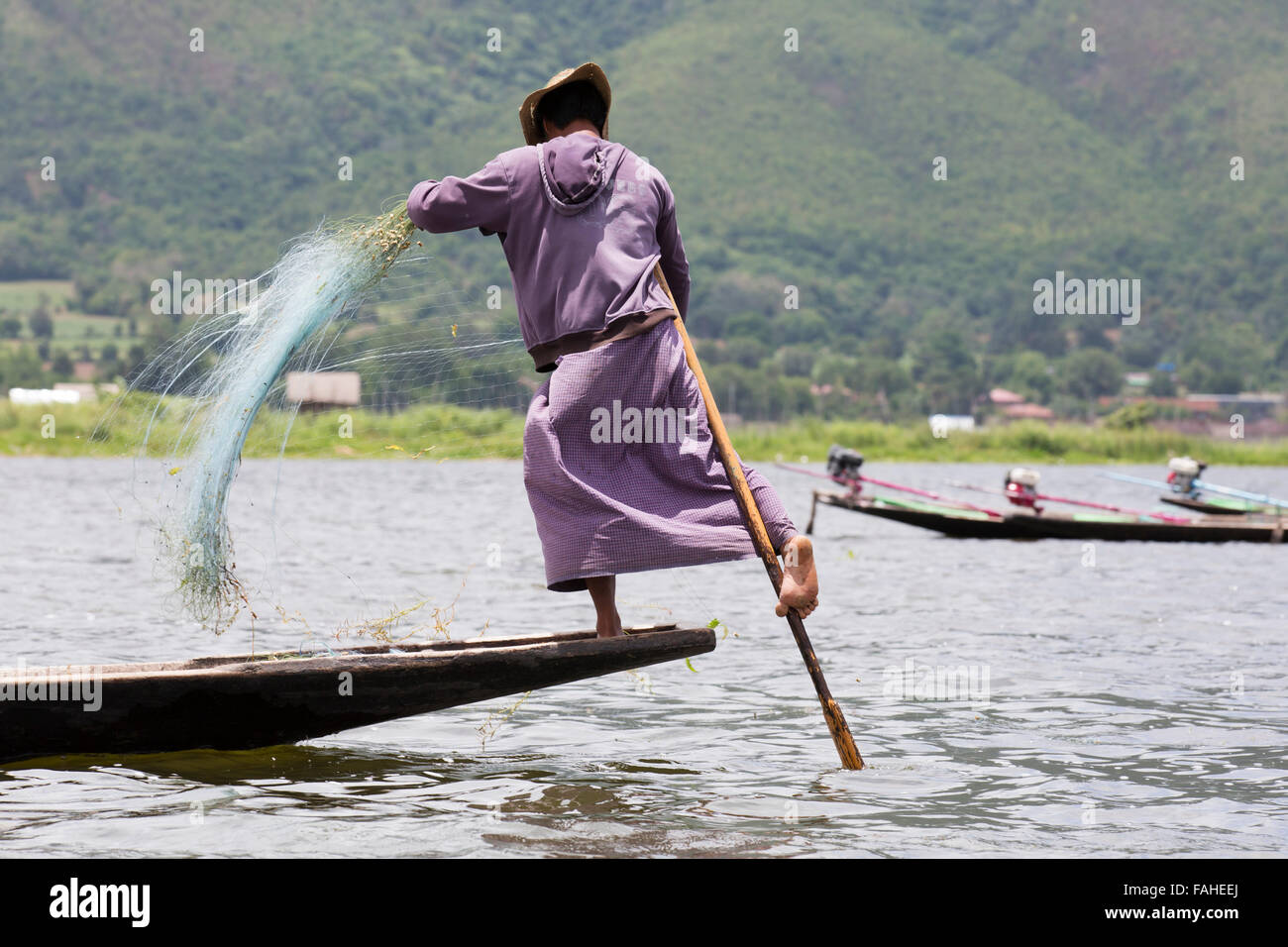 A fisherman from the Intha people rowing his boat on Inle Lake in Myanmar (Burma). The man is one of the leg rowers, who can row Stock Photo