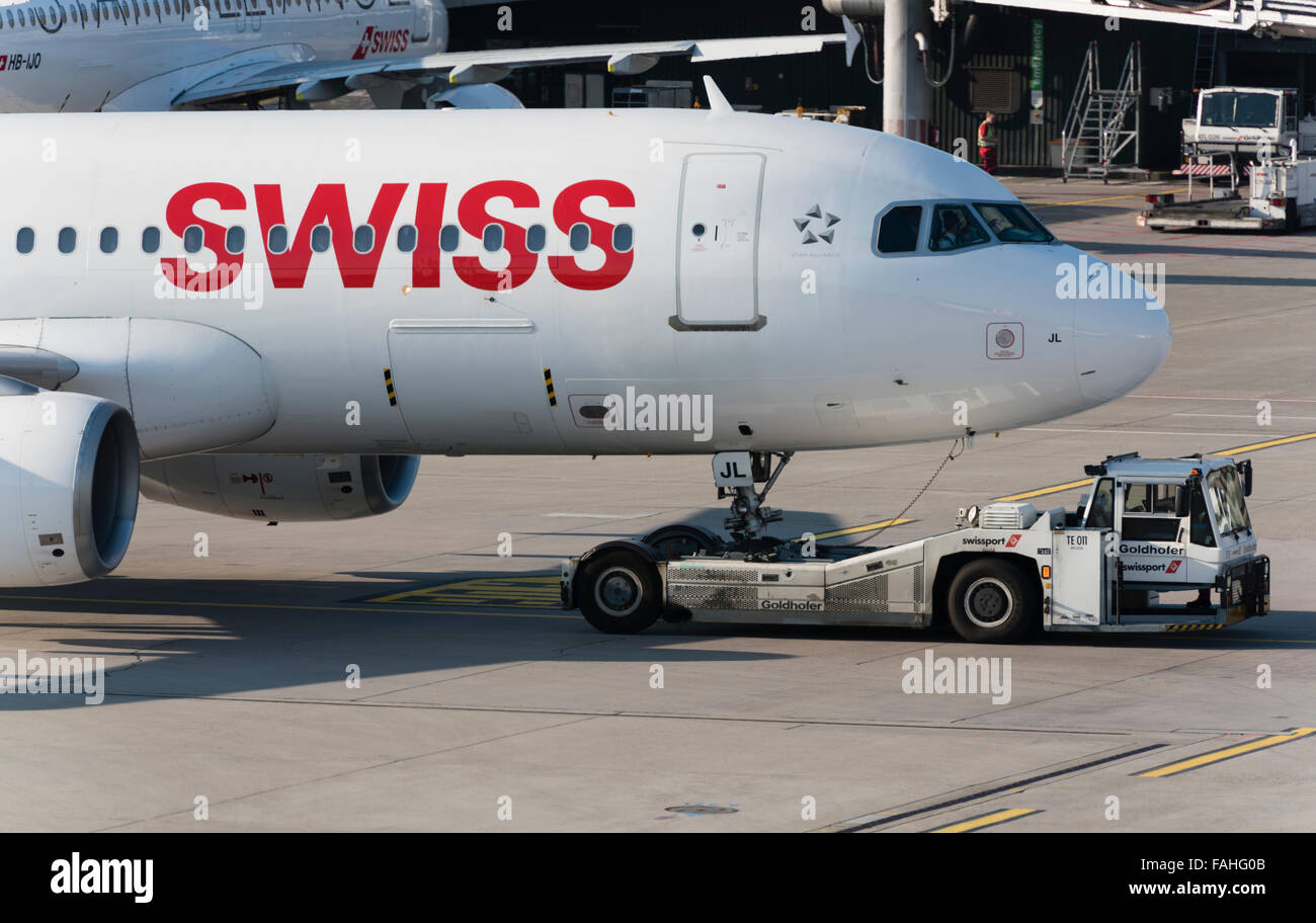 An aircraft tug is pushing an Airbus A320 of Swiss International Air Lines away from the gate at Zurich international airport. Stock Photo