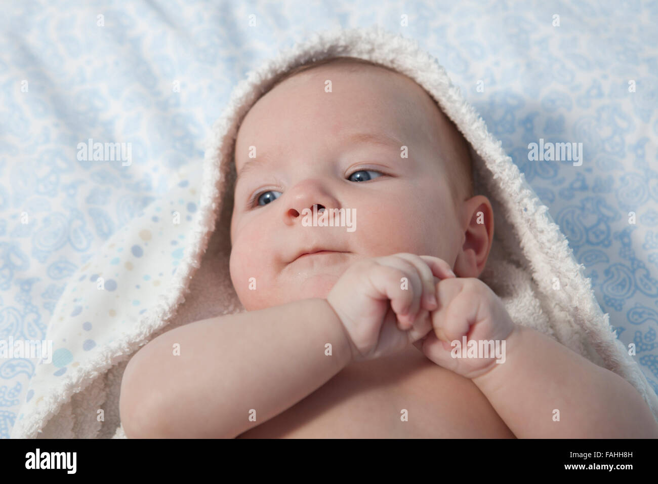 Cute three month baby wrapped bath towel after bath in bed at home