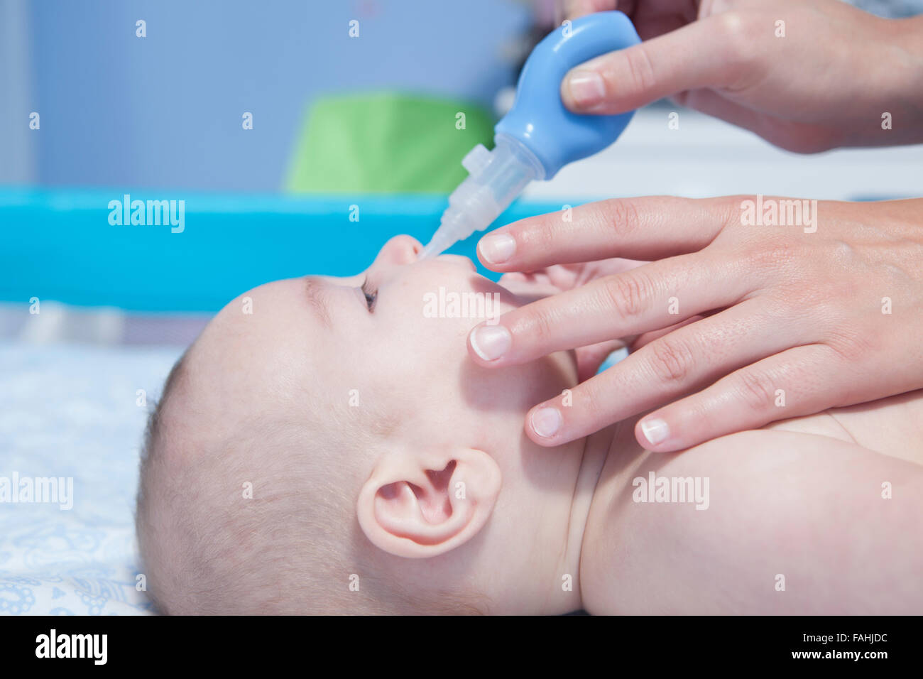 Mother using baby nasal aspirator. She is doing a mucus suction to three months baby boy Stock Photo