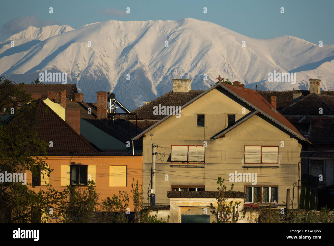Winter mountain houses in a romanian city with snowy mountains in the background Stock Photo
