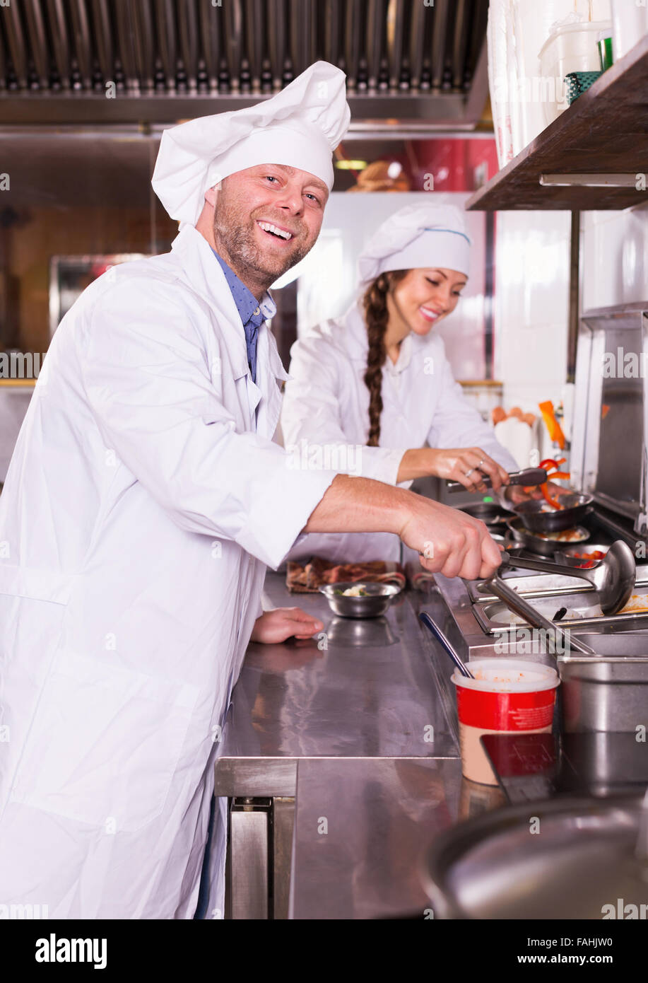 Cheerful happy cooks greeting customers at bistro kitchen and smiling Stock Photo