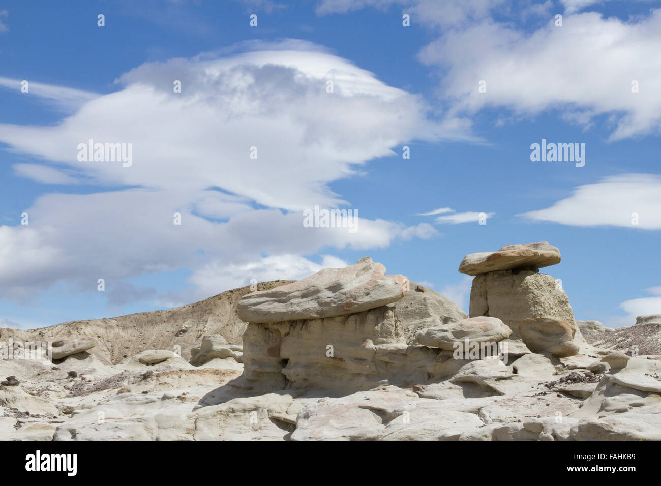 Lenticular clouds over rock formations in desert of La Leona Petrified Forest, Patagonia, Argentina. Stock Photo