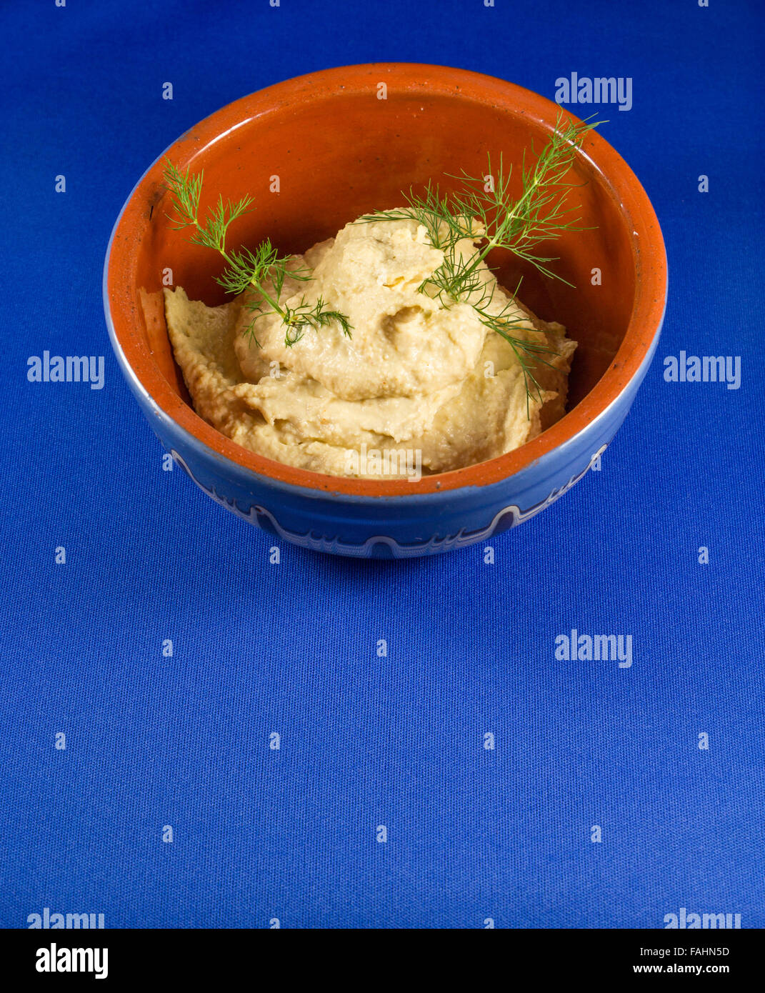 Hummus in traditional bowl with blue background Stock Photo Alamy