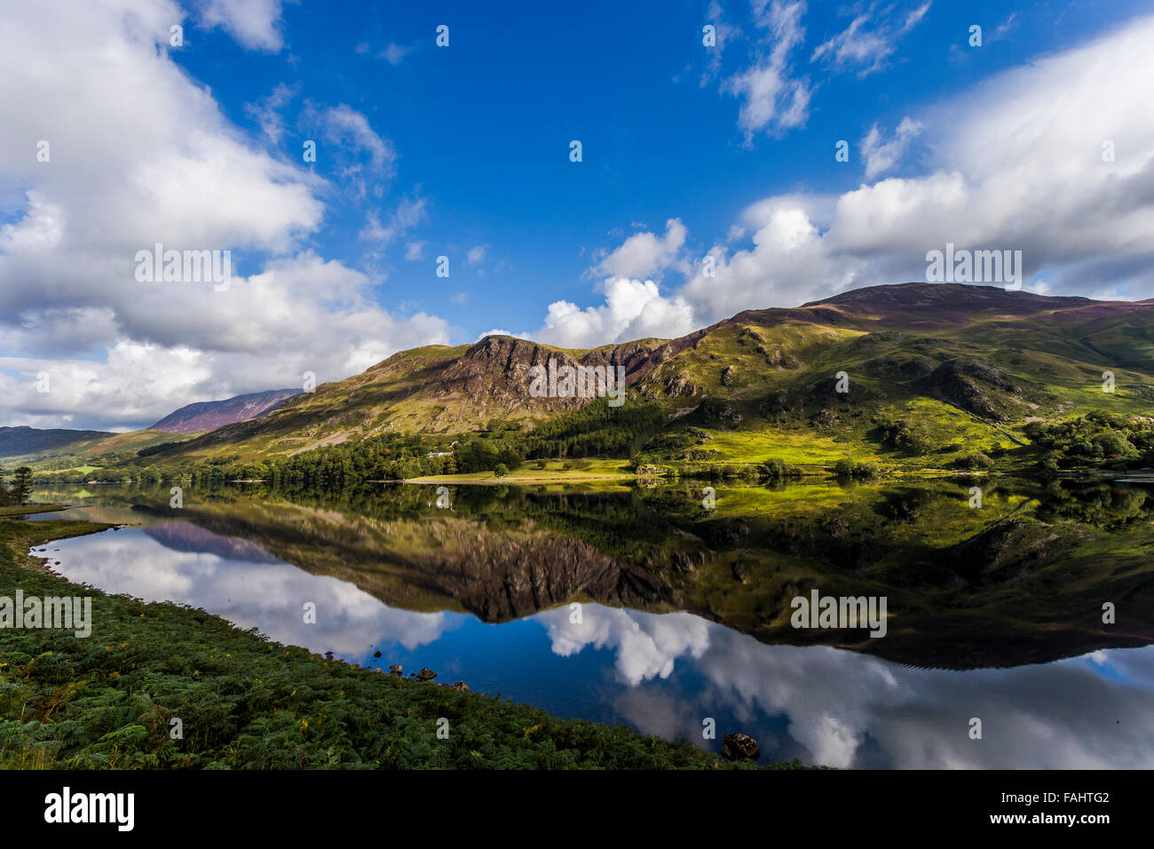 Lake Buttermere reflecting the surrounding hills on a bright sunny early autumn day Stock Photo