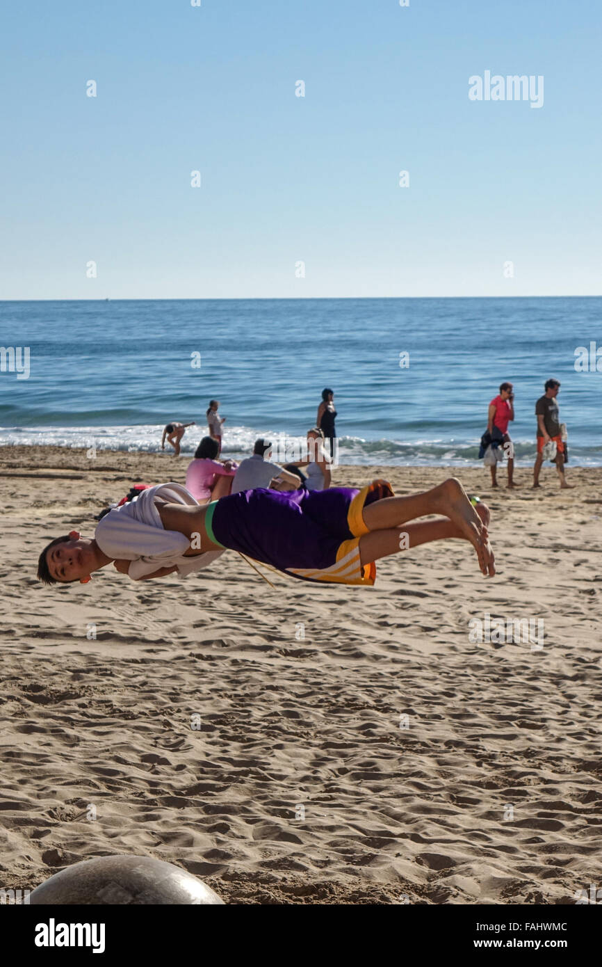 Young men practice tumbling, acrobatics, spinning and jumping on the Levante beach in Benidorm, Spain. Stock Photo