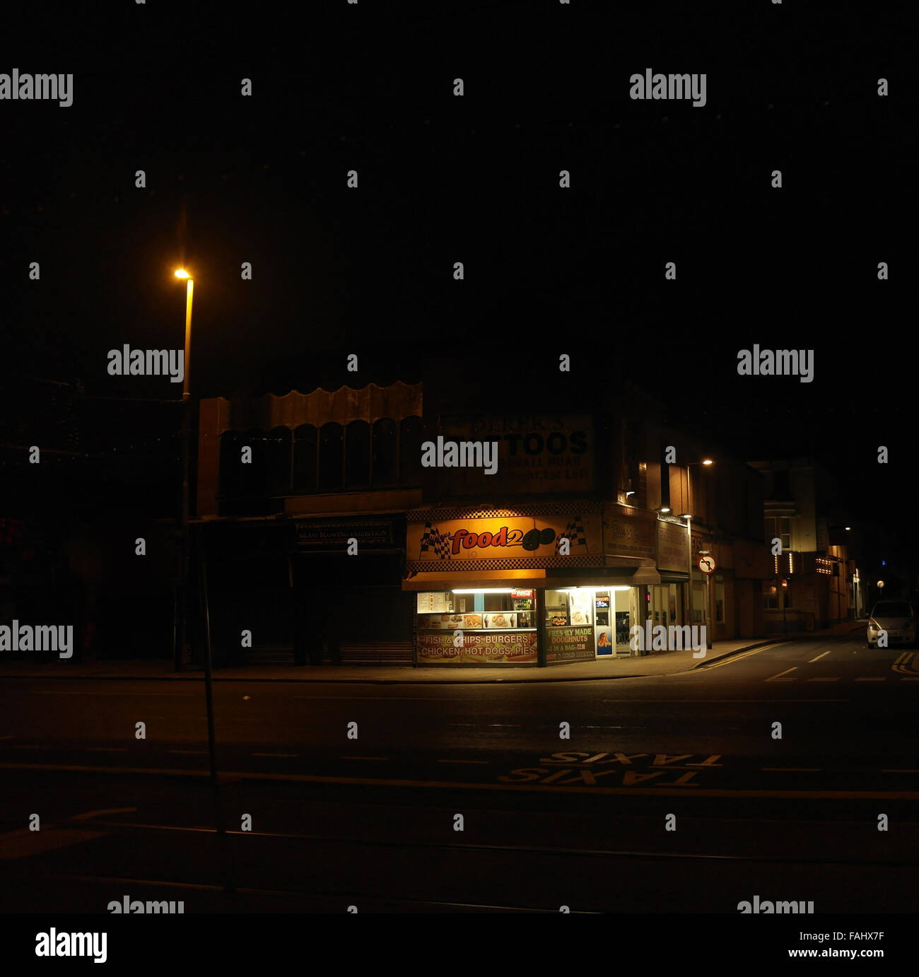 Night view illuminated 'Food 2 Go' shop, selling burgers, fish, chips, donuts, Central