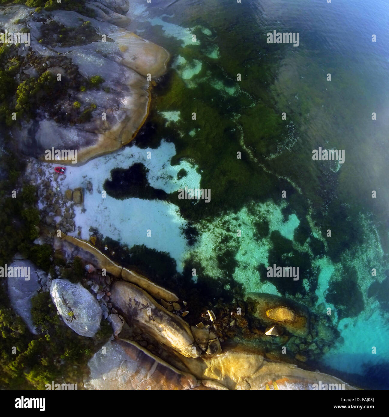 Aerial view of tiny red boat, seagrass meadows and rocky coast of Frenchman Bay, Albany, Western Australia Stock Photo
