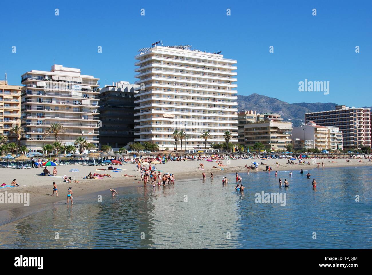 Holidaymakers relaxing on the beach with hotels and apartments to the