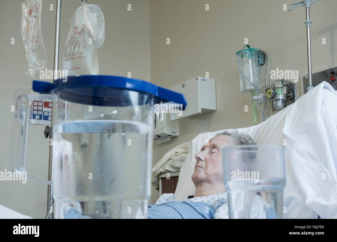 Elderly lady in her in bed on NHS hospital ward with jug of