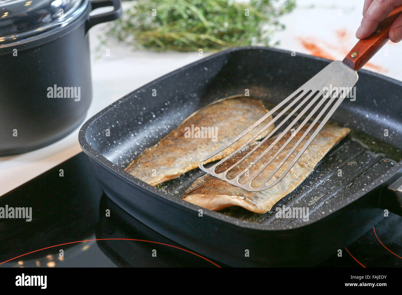 Frying fish on an electric stove Stock Photo