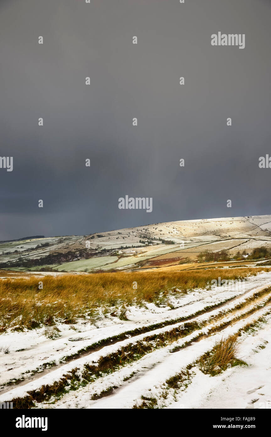 A snowy winter day in the High Peak area of Derbyshire. Dark snow clouds over a rough farm track. Stock Photo