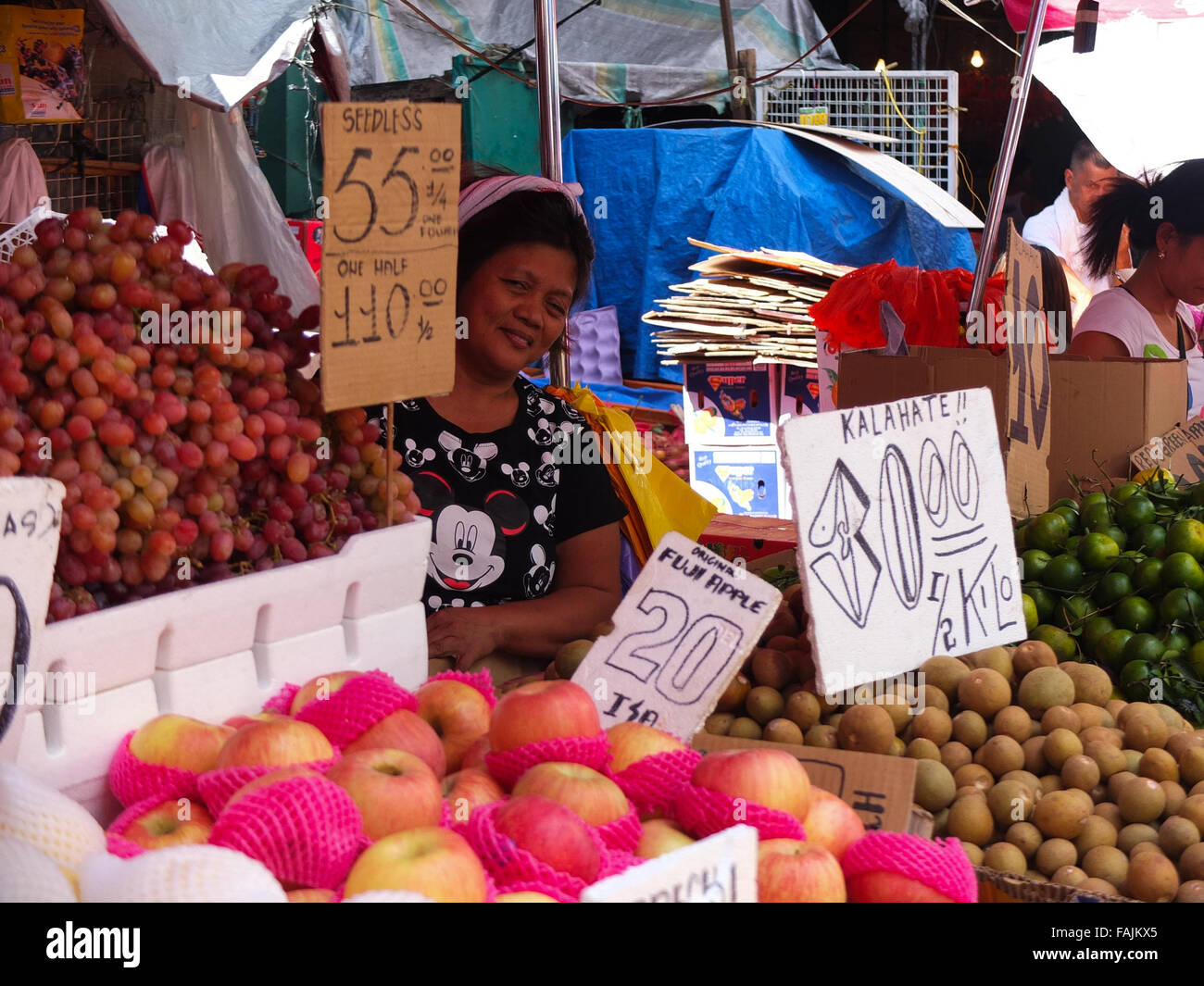 A fruit vendor smiling while being photographed at her fruits stand at Divisoria, manila. Filipinos anticipation of the last celebration on the calendar, The New Year's Eve with much merry making and superstitious belief on rounded fruits, It believes that it could bring luck. (Photo by Josefiel Rivera / Pacific Press) Stock Photo
