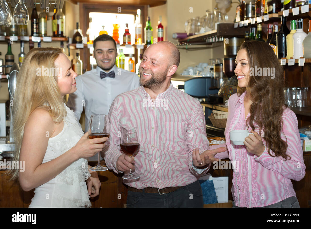 Group of cheerful smiling young adults hanging out in bar with drinks ...