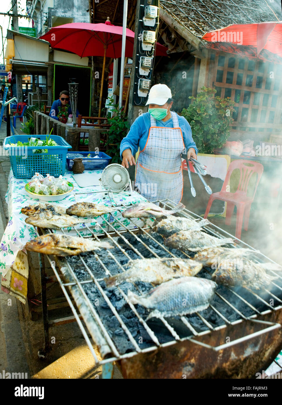 woman cooking fresh fish on BBQ Thailand Stock Photo