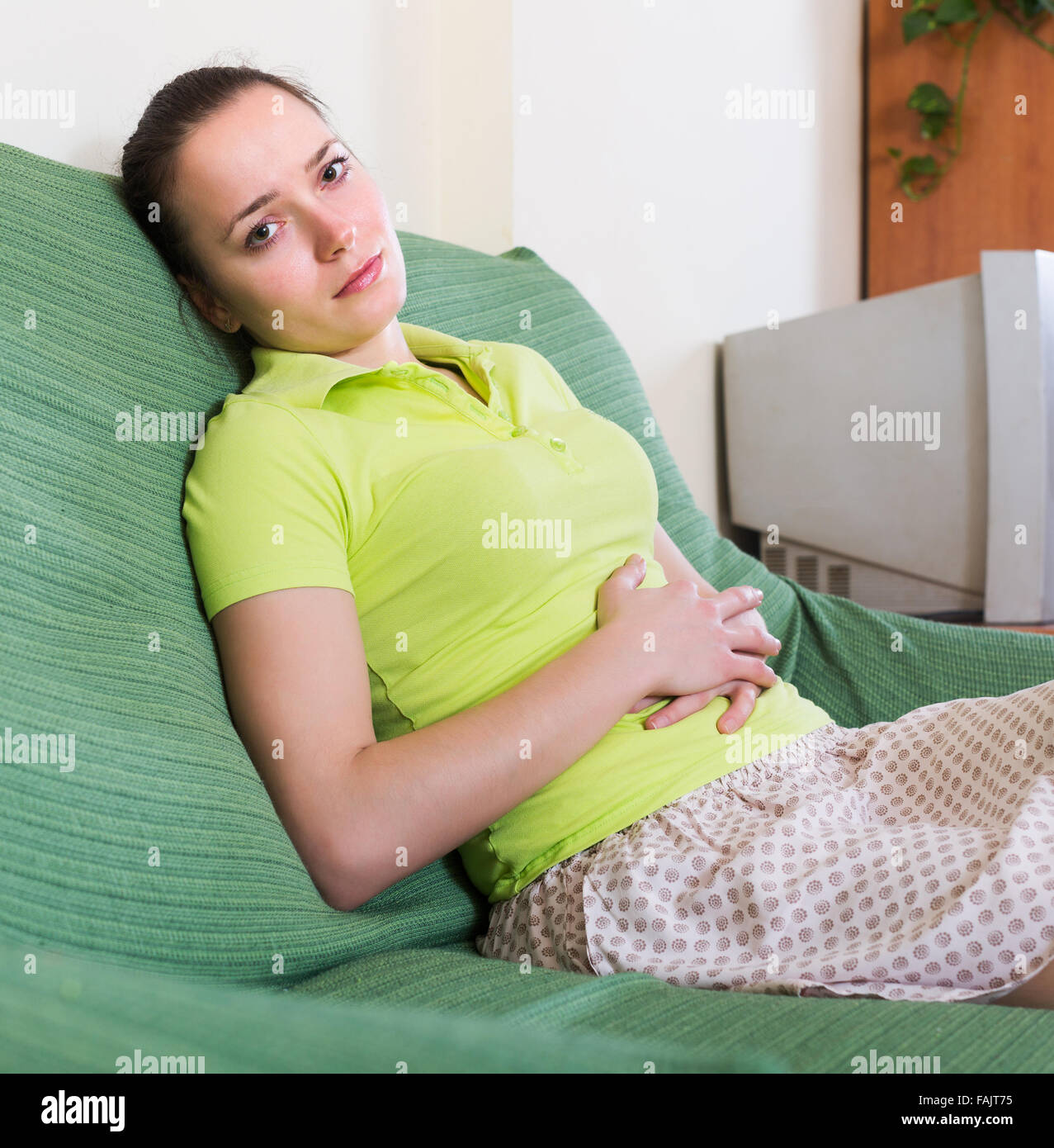Portrait of young upset girl having stomach aches at home Stock Photo