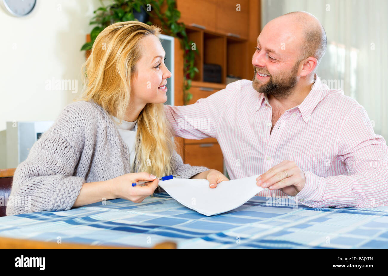 Husband and longhaired wife reading insurance contract and smiling