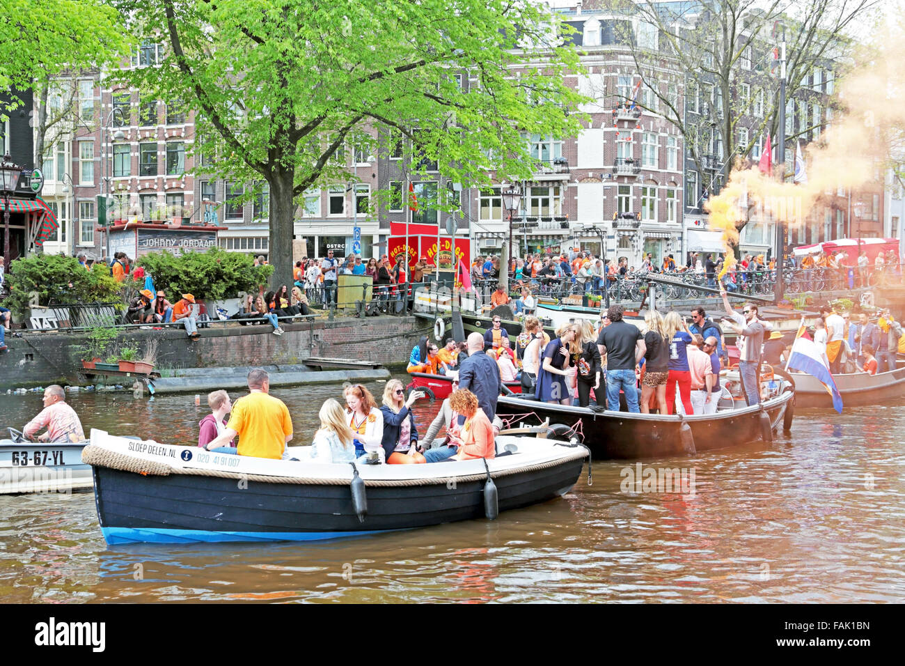 Canals of Amsterdam full of people in orange on boats during the celebration of kings day in tjhe Netherlands Stock Photo