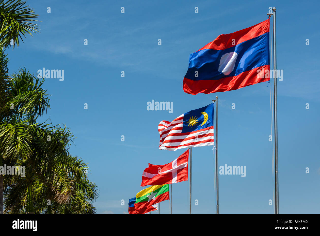Laotian, Malay, and Danish flag in the wind, blue sky, Sisowath Quay, Phnom Penh, Cambodia Stock Photo