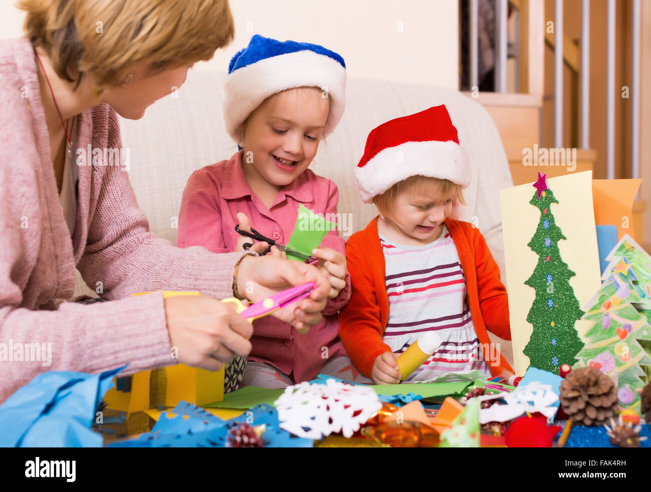 Young woman helping girls to make decoration for Xmas at home Stock ... - Helping Students With Decoration Solutions