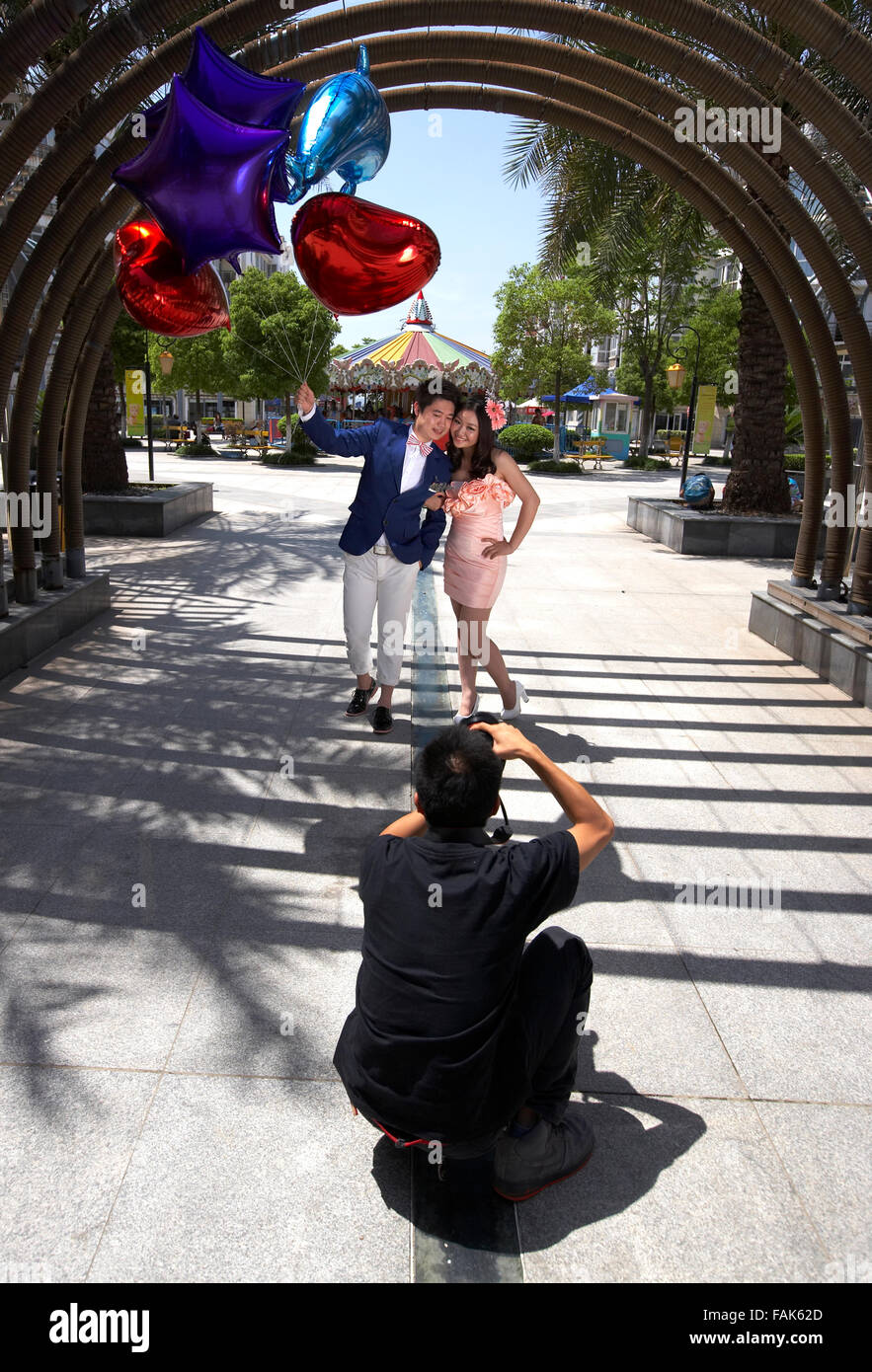 Vertical photo of young adult couple being photographed holding each other very closely with balloons. Stock Photo